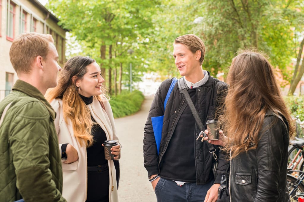 Fire videregående elever som snakker sammen ute